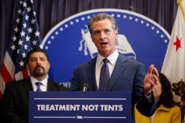 California Governor Gavin Newsom speaking at a podium during a news co<em></em>nference on the passing of Proposition 1, outlining plans to combat homelessness, at the Ro<em></em>nald Reagan State Building