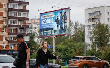 People walk near a banner with an advertising poster calling for military cons<em></em>cription in Moscow 