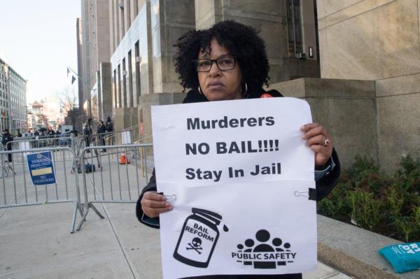 Critic of state bail reform is seen holding sign.