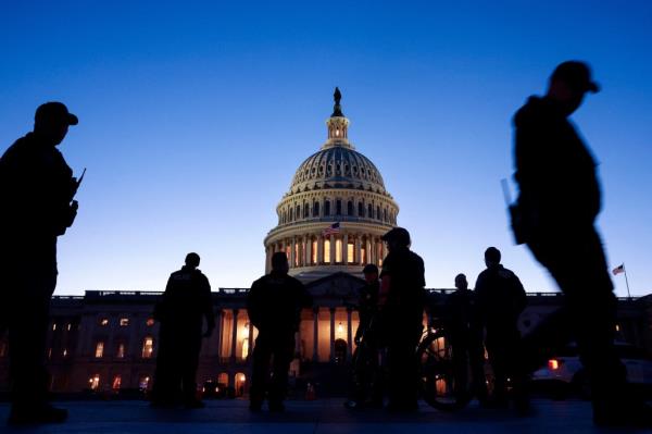 Silhouettes of a<em></em>bout 8 men can be seen on Capitol Hill at dusk
