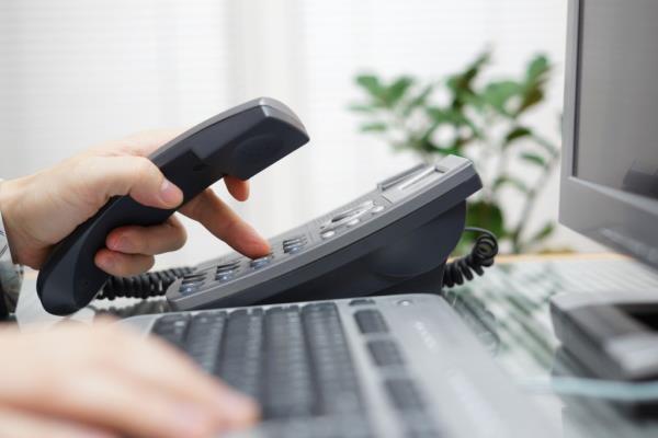 A stock photo shows a hand dialling a number on a desk phone