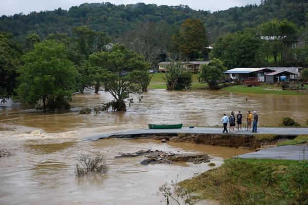 People stand near the flooded South Fork New River after being rescued  in Boone, North Carolina on Sept. 27, 2024.