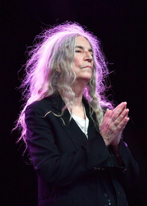 Patti Smith, with long hair and a black jacket, performing with the Patti Smith Quartet at Somerset House during the Summer Series, London, England.