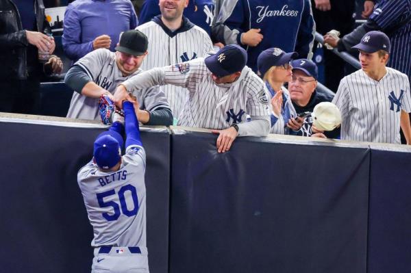 Yankees fans Austin Capobianco (gray jersey) and John Peter (white jersey) try to rip the ball out of the glove of Dodgers right fielder Mookie Betts (50) during Game 4 of the World Series at Yankee Stadium on Oct. 29, 2024.
