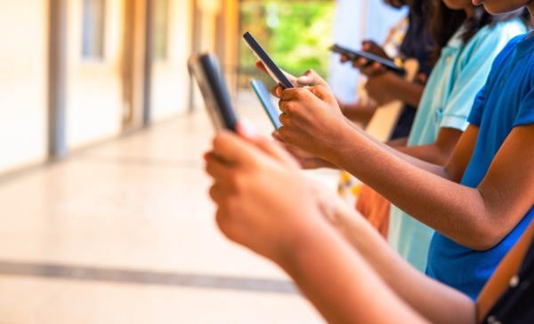 Close up shot, group of children hands busy using smartphone at school corridor 